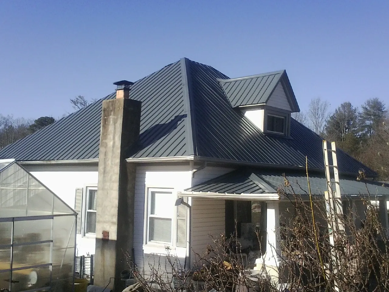 Dark blue standing seam metal roof on a white farmhouse with dormer — Slate & Tile Roof Repair by Roofing Brothers in Monsey
