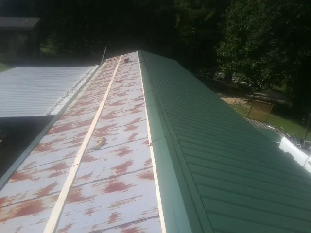 Old rusted panels beside newly installed green metal roofing — Wind Damage Roof Repair by Roofing Brothers in Monsey