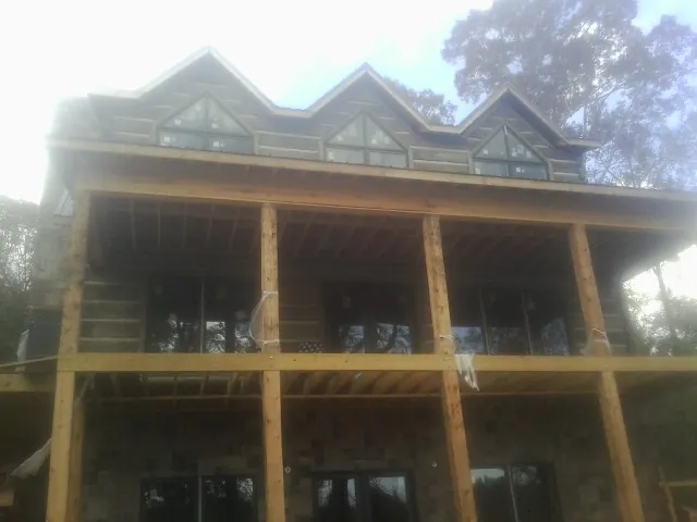 Dormers and porch framing on a large log home under construction — Roof Coating work by our crew in Monsey