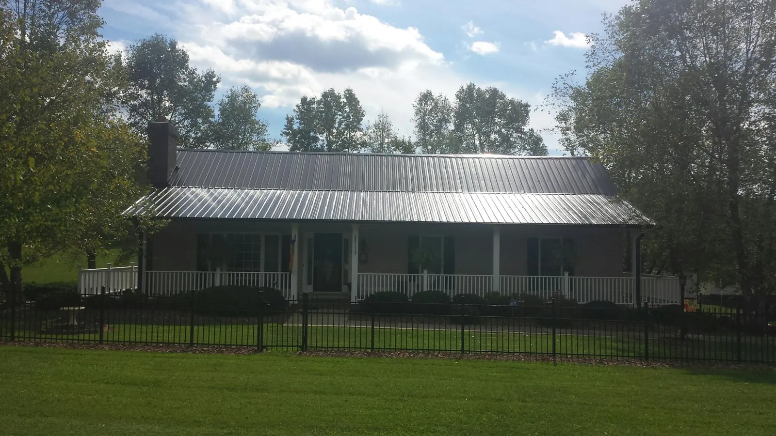 Gray metal roof on a brick ranch with a full width front porch — Gutter Guard Installation work by our crew in Monsey