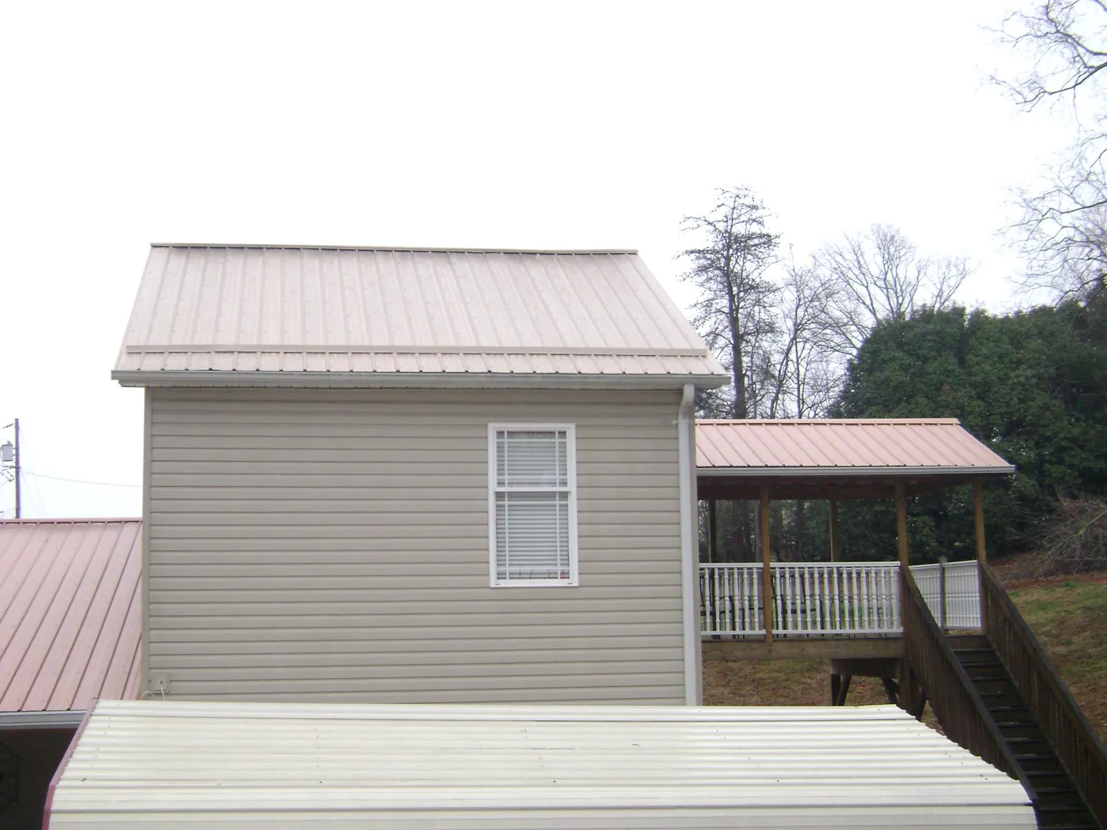 Tan metal roofs on a two story addition and attached porch, from a Roof Replacement job in Monsey