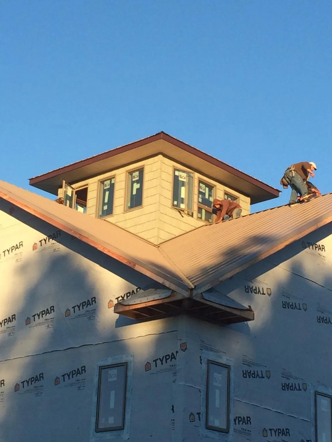 Roofers working around a rooftop cupola on a new metal roof at sunset — Roof Waterproofing in Monsey by Roofing Brothers